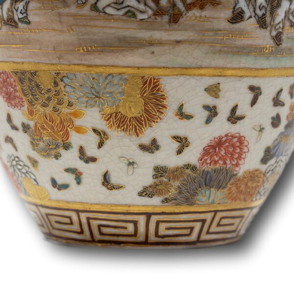 Close up of the butterfly and flower decoration on the lower half with greek key border